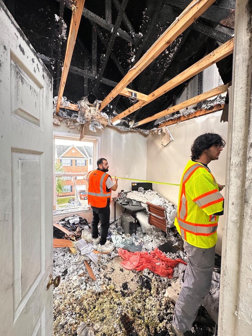 Measuring a fire-damaged bedroom for the estimate